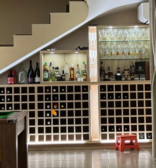 Une cave à vin aménagée sous un escalier, avec éclairage intégré